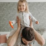Father and daughter sharing a playful moment in a cozy bedroom, enhancing family bond.